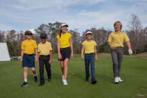 Young golfers walking together across a golf course during a Play Yellow event.