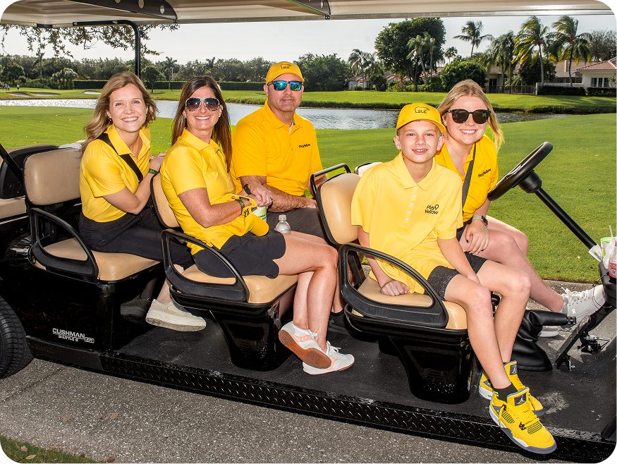 Play Yellow participants riding together in a golf cart on a golf course.