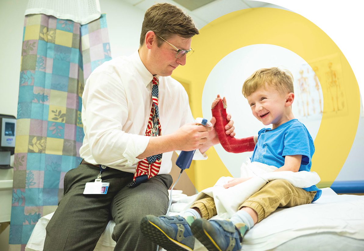 Doctor helping a young child with a cast during a hospital visit.