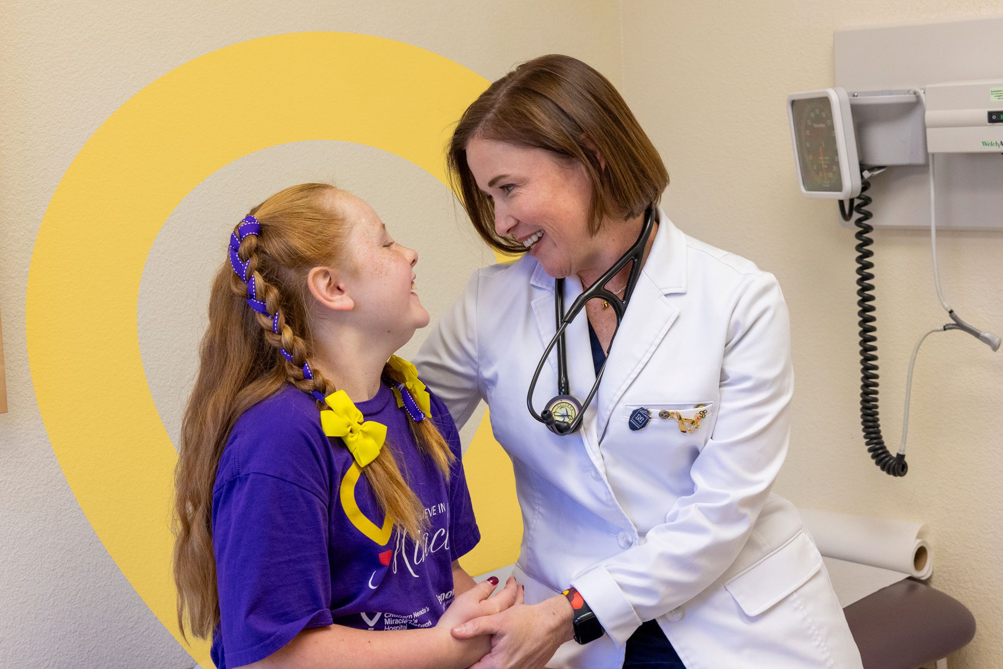 Doctor smiling with a young patient in an exam room.
